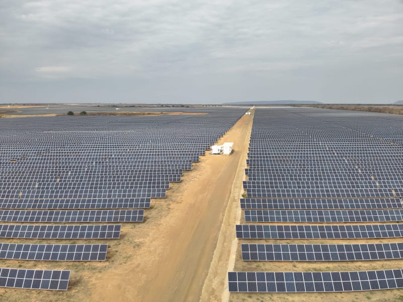 Usina fotovoltaica de grande porte em campo aberto, com longas fileiras de módulos e via de acesso central